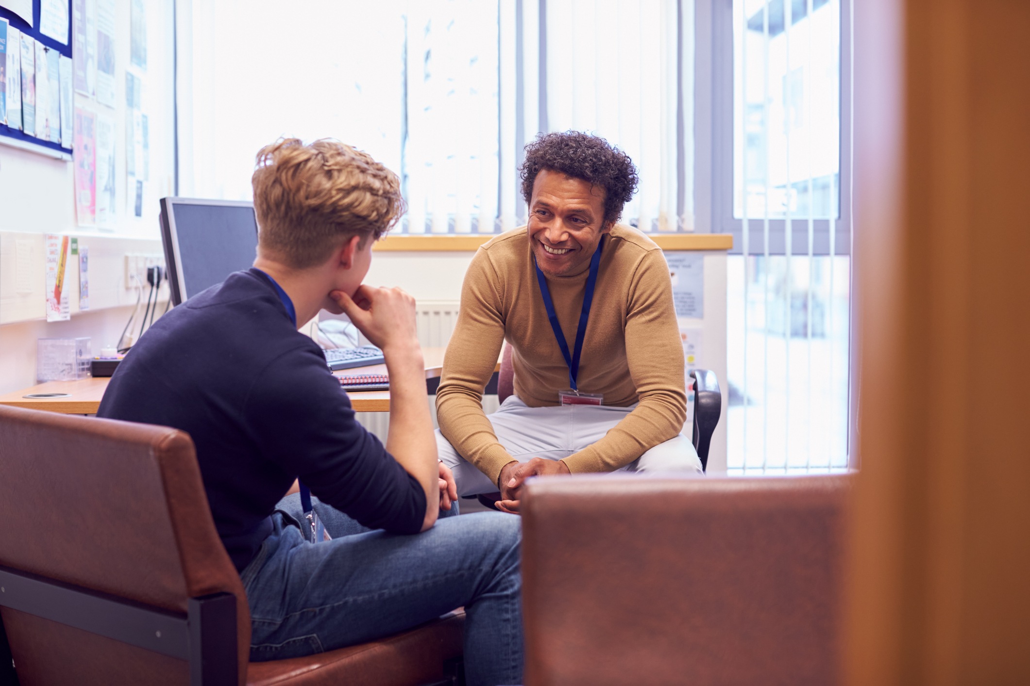  A male student talks with a financial counselor about money while sitting in his office.