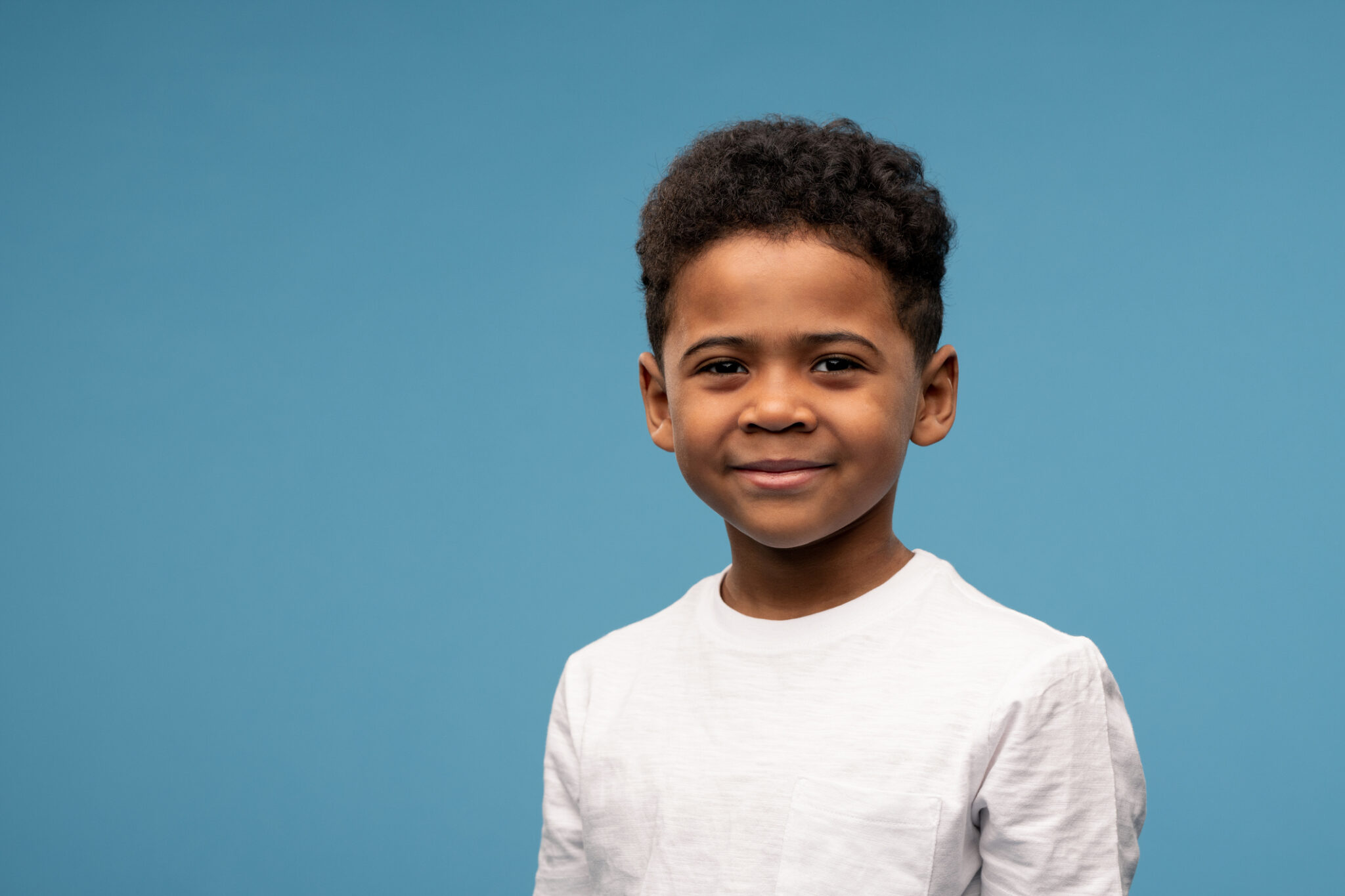 Happy little boy of African ethnicity in t-shirt standing in front of ...