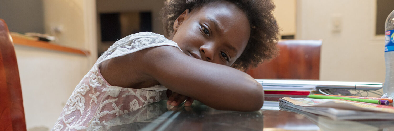 Afro-Latino girl from Bogotá Colombia, 5 to 8 years old, looking at the camera in a portrait with a sad and lonely face due to everything that is happening in the face of the pandemic
