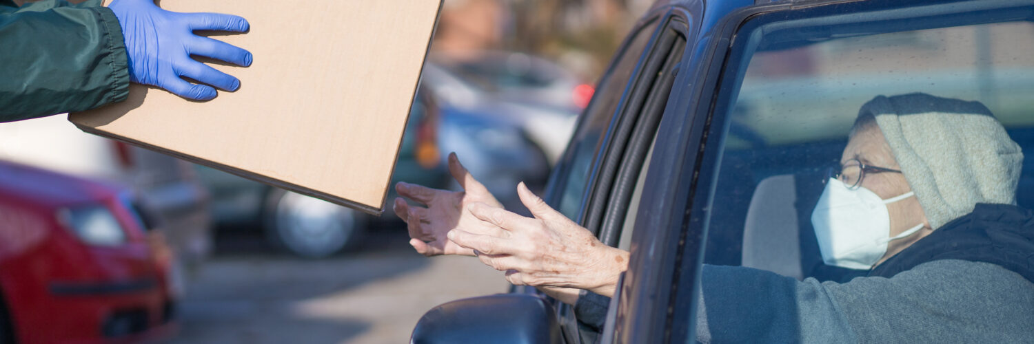 food bank box handed to needy elderly person in vehicle