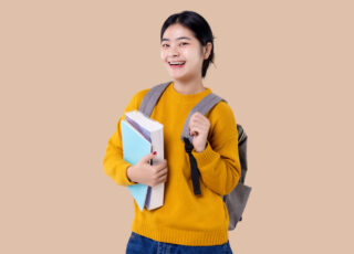 Young Asian student girl holding books and backpack on isolated background